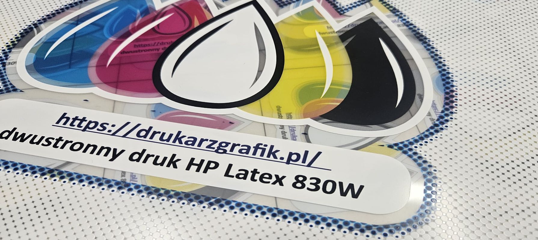 Kreatywne wykorzystanie białego tuszu w druku HP Latex 830W pokazane na logo DrukarzGrafik na materiale transparentnym.